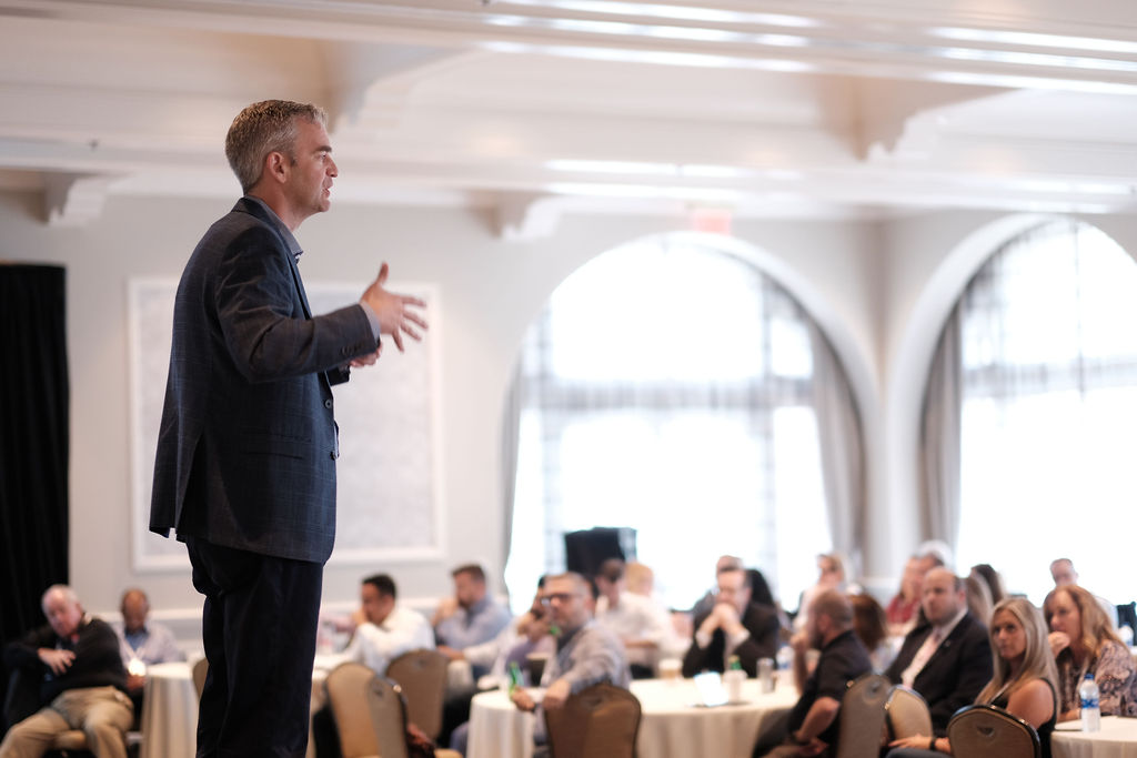 man speaking onstage conference