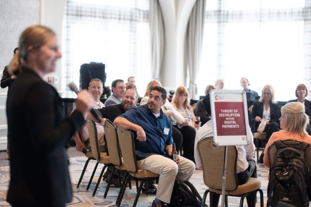 A speaker presenting to an audience seated in a conference room, focused on a topic about digital payments.business conference hyatt hutington beach photographer nicole caldwell