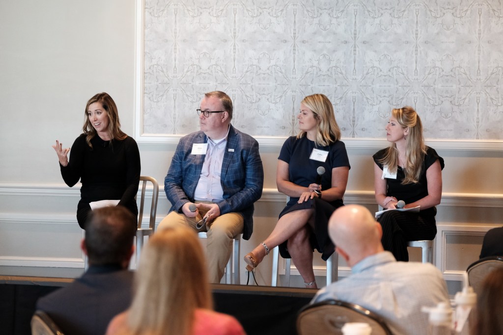 A panel discussion featuring four speakers at a corporate retreat event, with the audience partially visible in the foreground. Huntington Beach hyatt orange county business corporate event photographer nicole caldwell