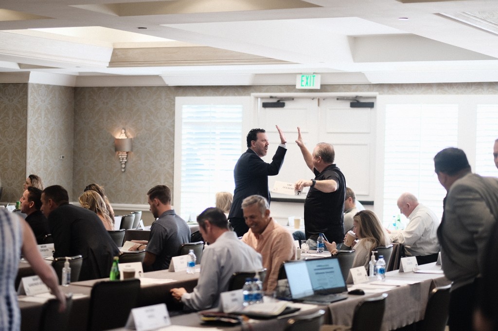 Participants engaging in a lively discussion during a conference in a well-decorated meeting room. business conference surf and sand hotel laguna beach photographer nicole caldwell