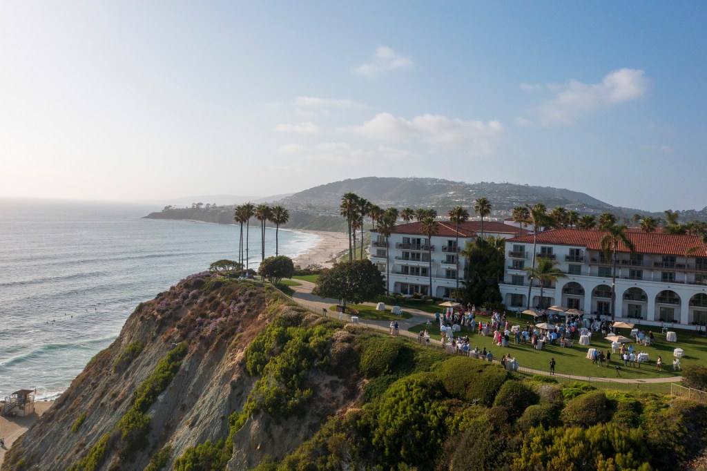 Aerial view of the Ritz Carlton in Laguna Niguel, California, featuring palm trees, a beach, and a gathering on the lawn. corporate business event photographe nicole cadlwell
